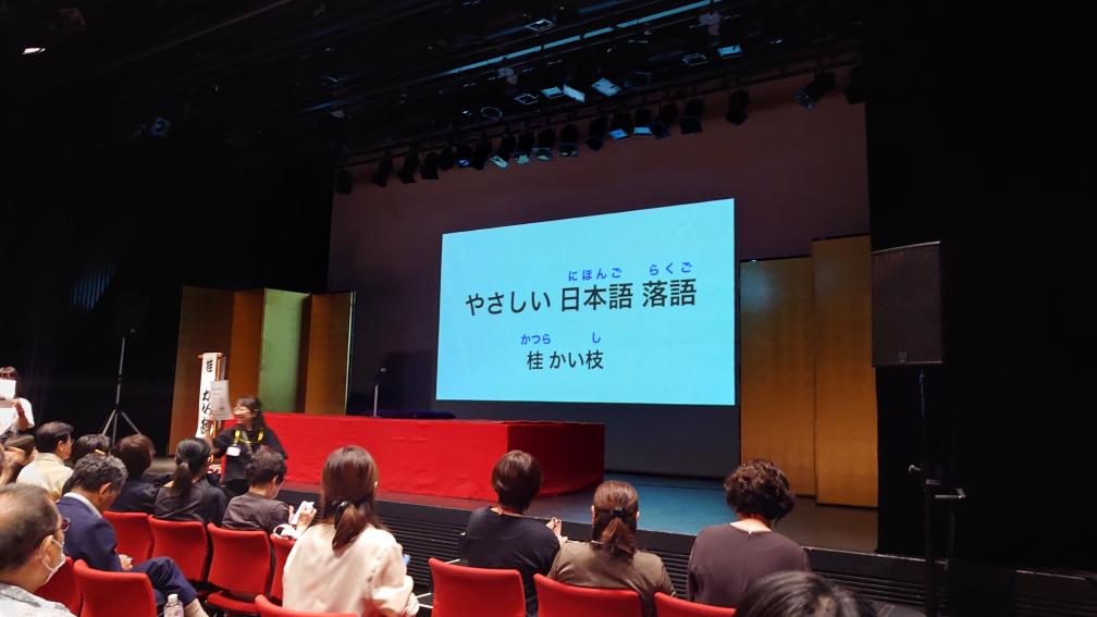 「やさしい日本語落語」開演前の会場。スライドに「やさしい日本語落語」と投影されている。